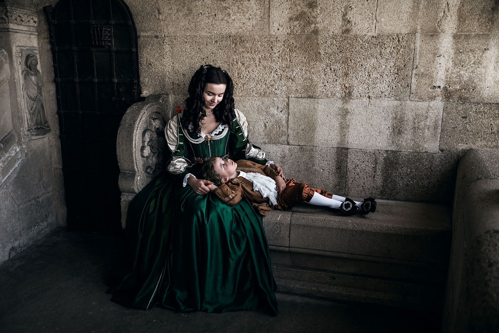 zrinyi ilona and rakoczi ferenc inspired advertising photo shoot at the castle of liechtenstein by fashion historian and stylist katalina sasdy. helena zrinski is sitting on a stone bench on the terrace of the castle with her little son rakoczi ferenc II. the boy is lying in his mothers lap. they are looking at eachother lovingly. both of them are wearing costumes in stlye of the 17th century.